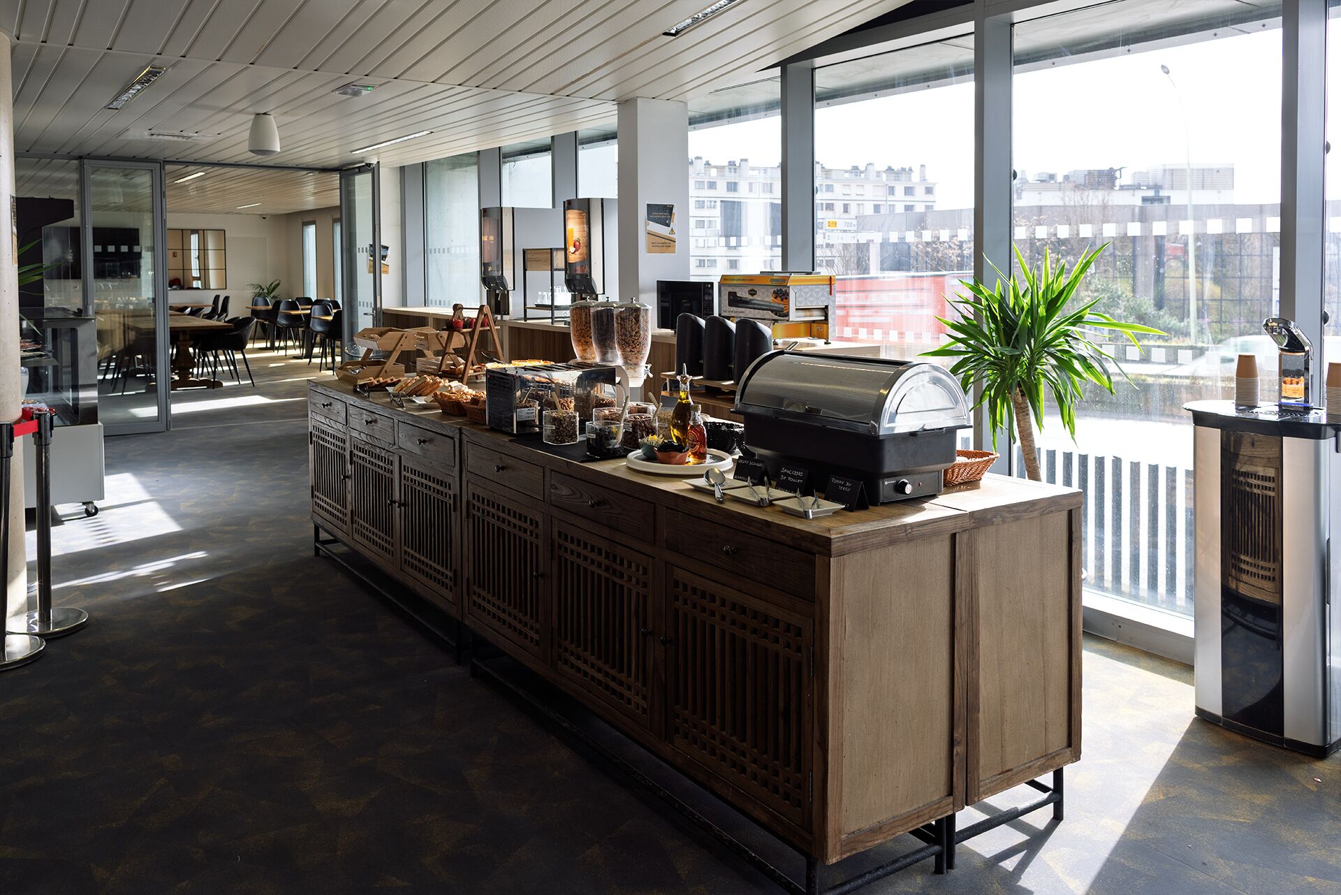 Un área de cocina moderna con una estación de café, un ventanal y vistas a la ciudad.