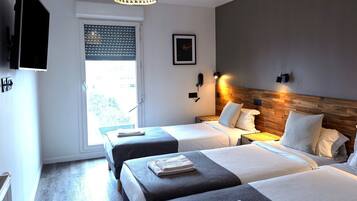 A hotel room with two beds, a wooden headboard, a wall-mounted phone, and a window with blinds.