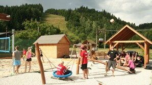 Une aire de jeux avec des balançoires, une balançoire à bascule et une petite cabane en bois.