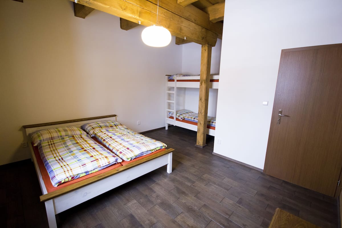 A room with a wooden bed, a bunk bed, and a wardrobe.
