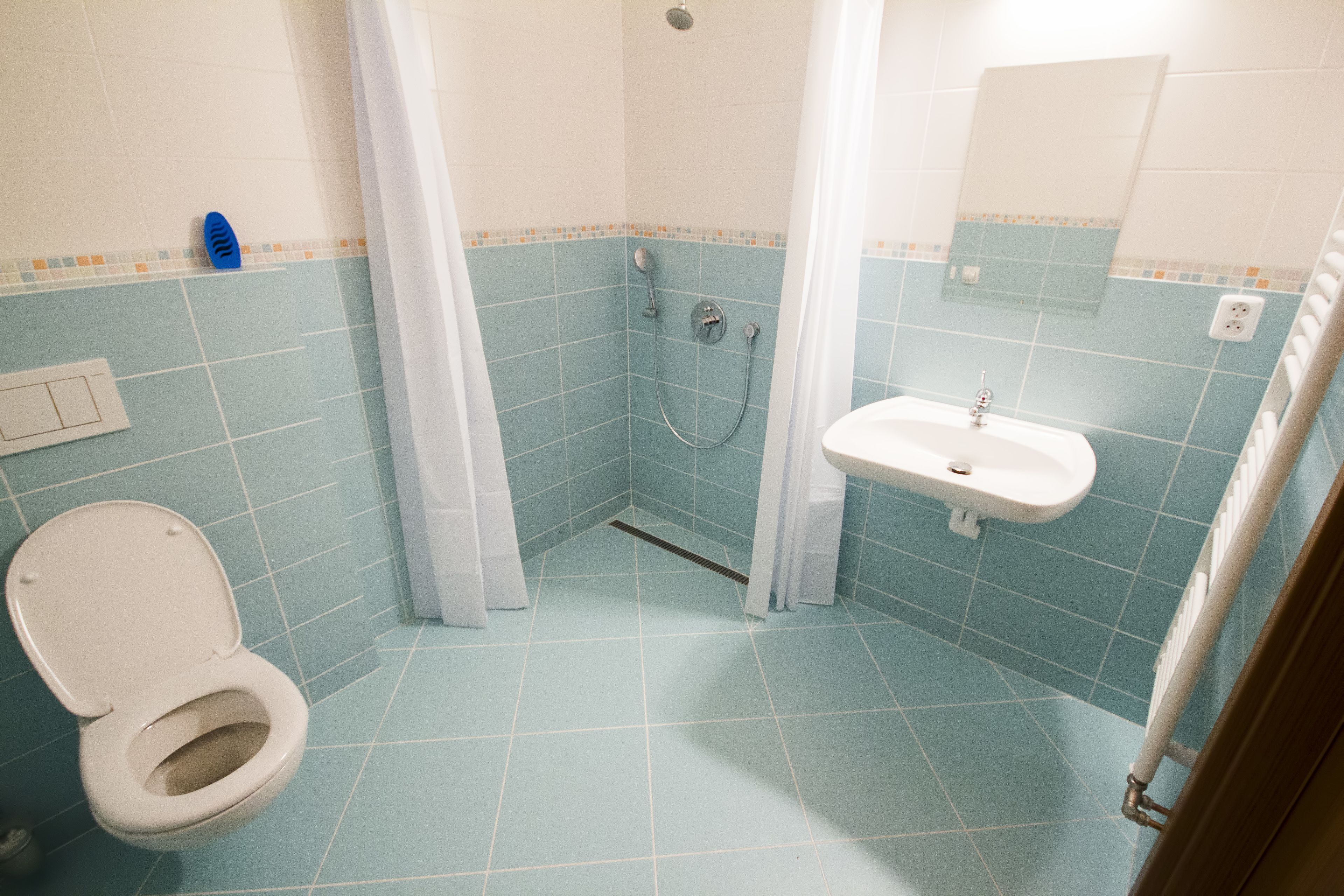 A bathroom with a toilet, sink, shower, and tiled walls.