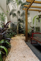 Un sendero bordeado de diferentes plantas y una estructura de pérgola de madera.