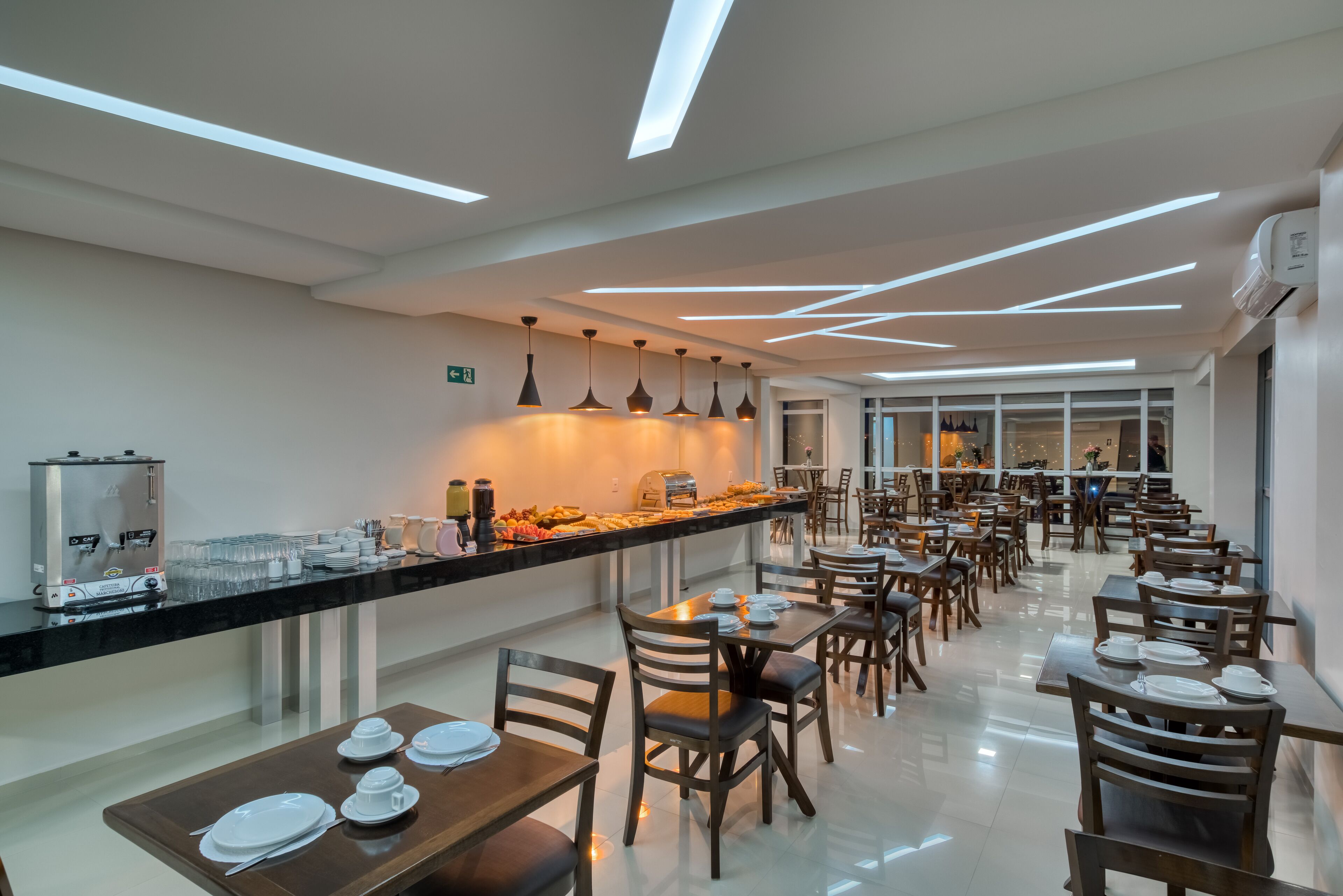 Un comedor moderno con un bufé, mesas y sillas ordenadas y un diseño limpio y contemporáneo.