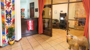 A reception area with a desk, a potted plant, a red curtain, and a bull statue.