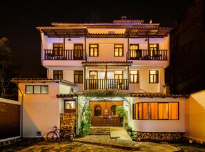 A two-story building with a balcony on the upper floor, a wooden door with a red ribbon, and a bicycle parked outside. - Hotel Santa Cruz (Huaraz)