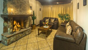 Una sala de estar acogedora con chimenea de piedra, sofás de cuero, una mesa de centro y una planta de cactus.