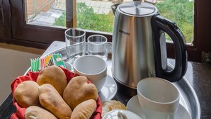 Una bandeja con pan, una tetera, tazas y un azucarero sobre una mesa junto a una ventana con vistas a la ciudad.