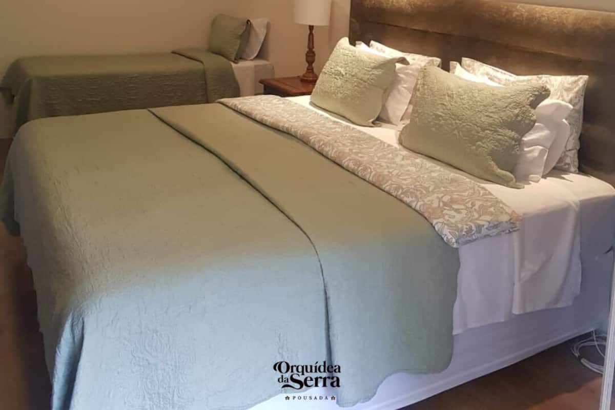 A hotel room with two beds, a nightstand, a lamp, and framed artwork on the walls.
