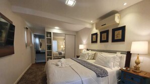 A hotel room with a large bed, bedside tables, a wardrobe, and a mirror. - Pousada Orquídea da Serra (Petrópolis)