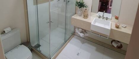 A modern bathroom with a glass-enclosed shower, a toilet, and a vanity with a mirror.