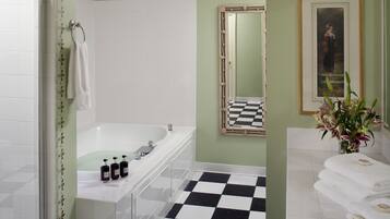 A bathroom with a white bathtub, a checkered floor, and a mirror with a black and white frame.