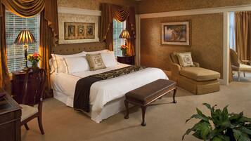 A spacious bedroom with a large bed, a sitting area with a chair, and a desk.