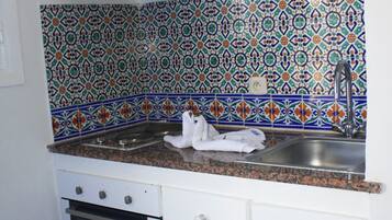 A kitchen with a patterned backsplash, a stainless steel sink, and a built-in oven.