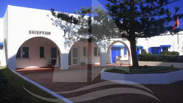 A building with a reception area, arched walkways, and a tree in the foreground.