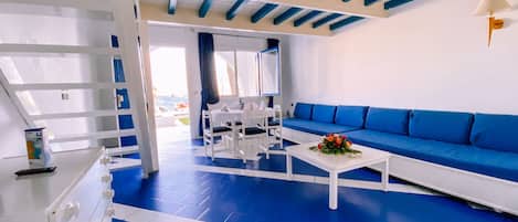 A room with a blue and white color scheme, featuring a white sofa, a white table, and a white cabinet.