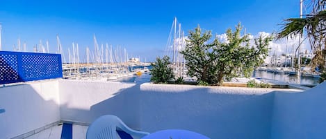 Una terraza con mesa y sillas con vistas a un puerto deportivo lleno de barcos.