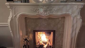 A fireplace with ornate white mantel and a fire burning inside.