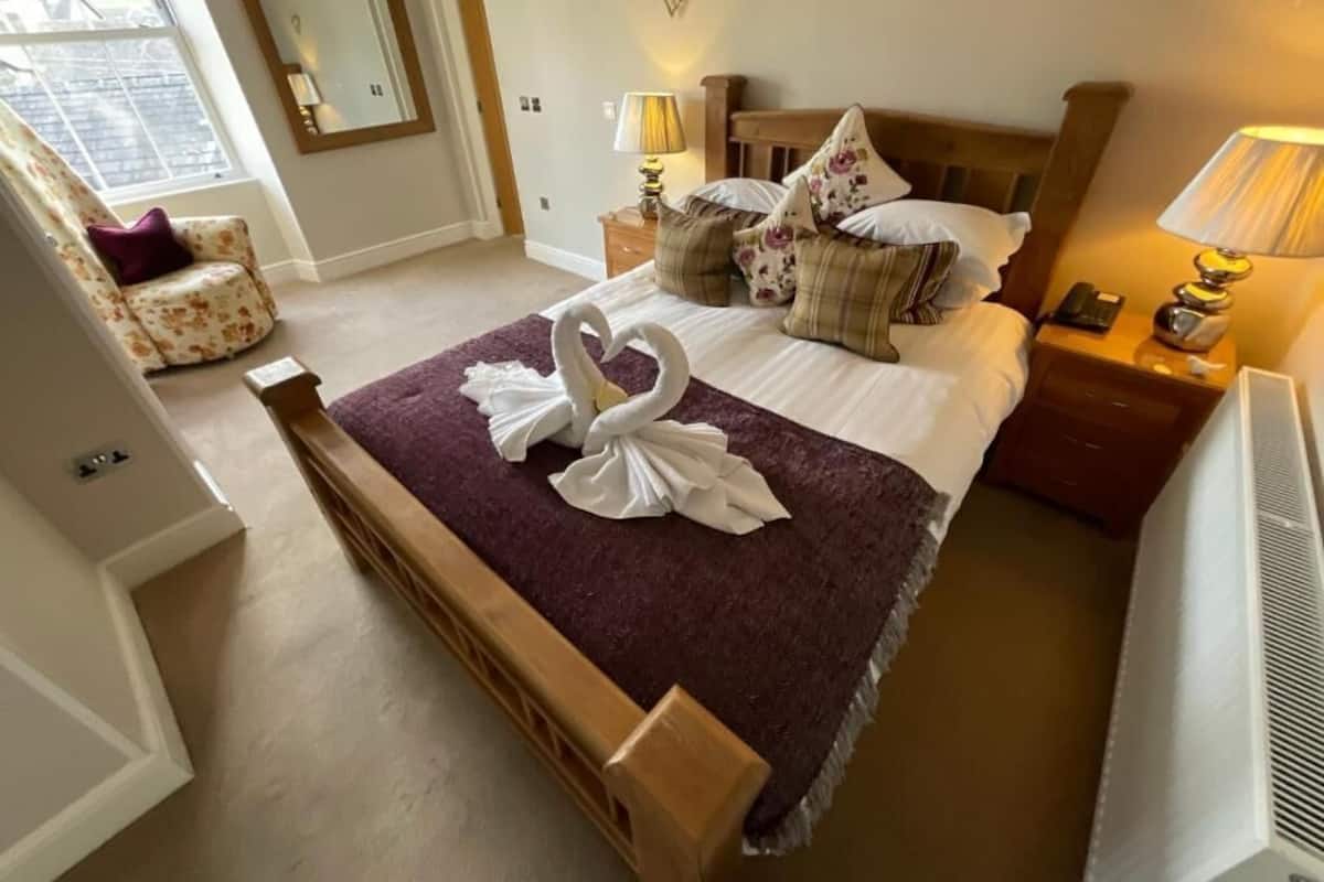 A neatly arranged bedroom with a bed, a chair, a bedside table, and a lamp.