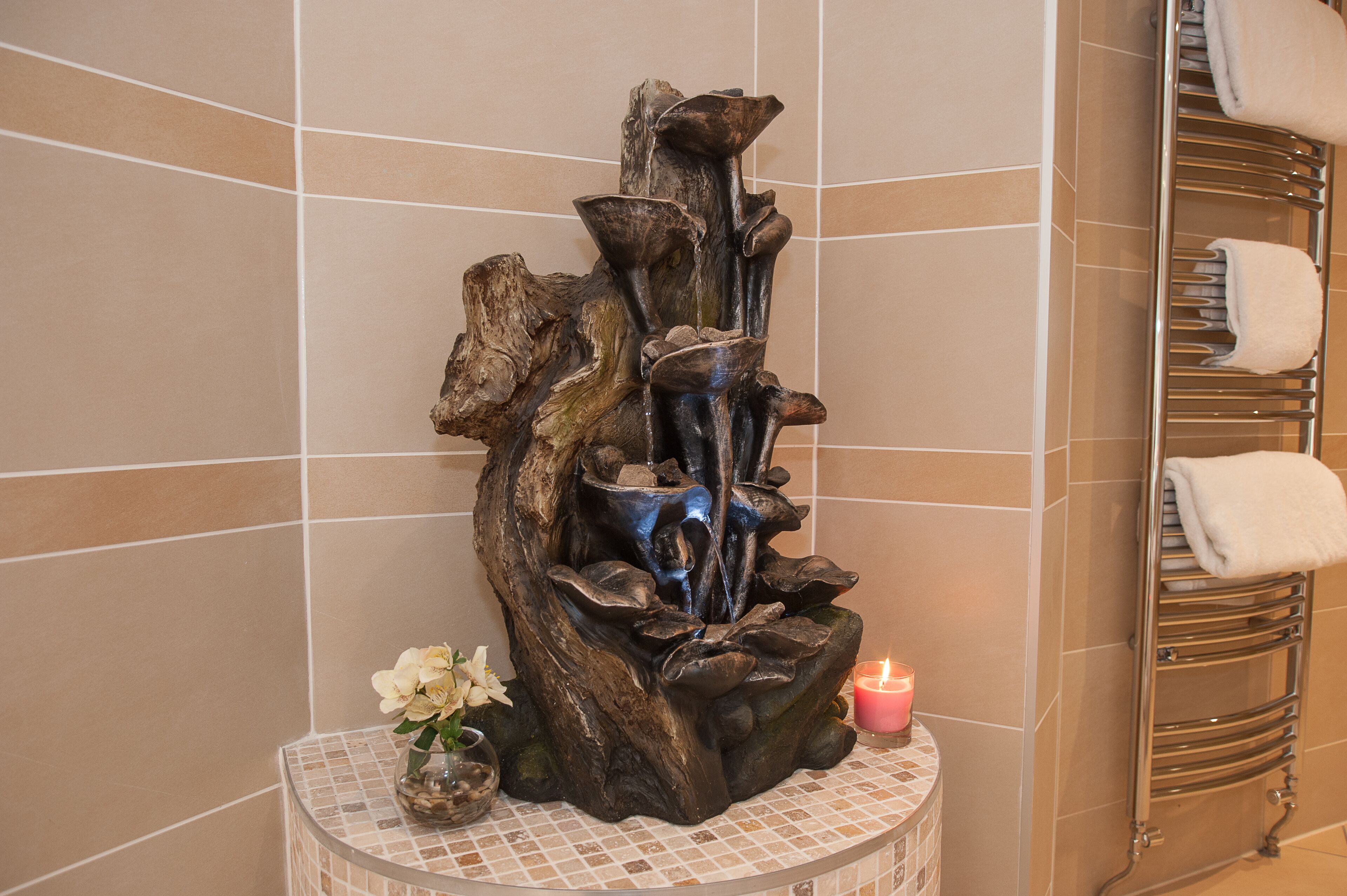 A bathroom with a wooden sculpture centerpiece, a towel rack, and a small vase with flowers.