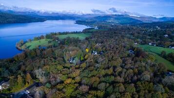An aerial view of a lakeside property with a dense forest, a small lake, and a few scattered houses.