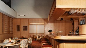 A bar area with wooden bar stools, a counter with a television, and a wall-mounted wine rack. - Auberge de la Baie (Caraquet)