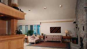 A spacious living room with a fireplace, a striped sofa, a wooden cabinet, and a stone wall. - Auberge de la Baie (Caraquet)