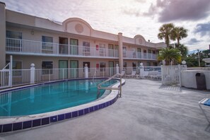 A hotel with a swimming pool, multiple balconies, and palm trees. - Budget Inn Cocoa (Cocoa)