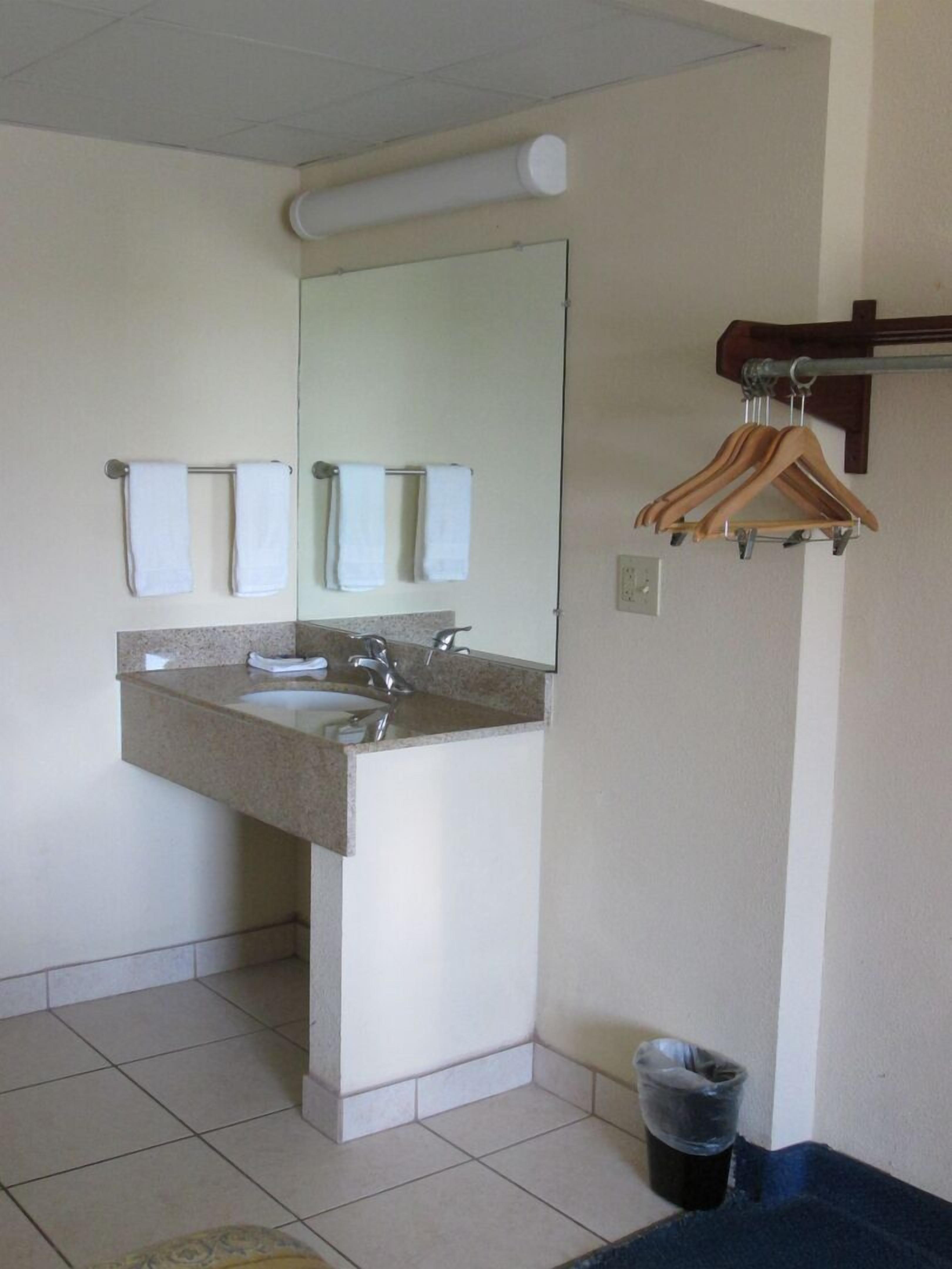 A bathroom with a sink, mirror, and hanging towels.