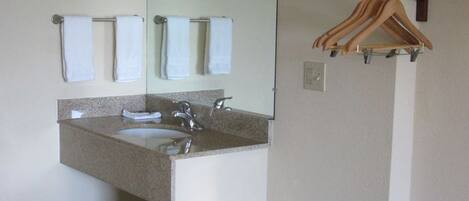 A bathroom with a sink, mirror, and hanging towels.