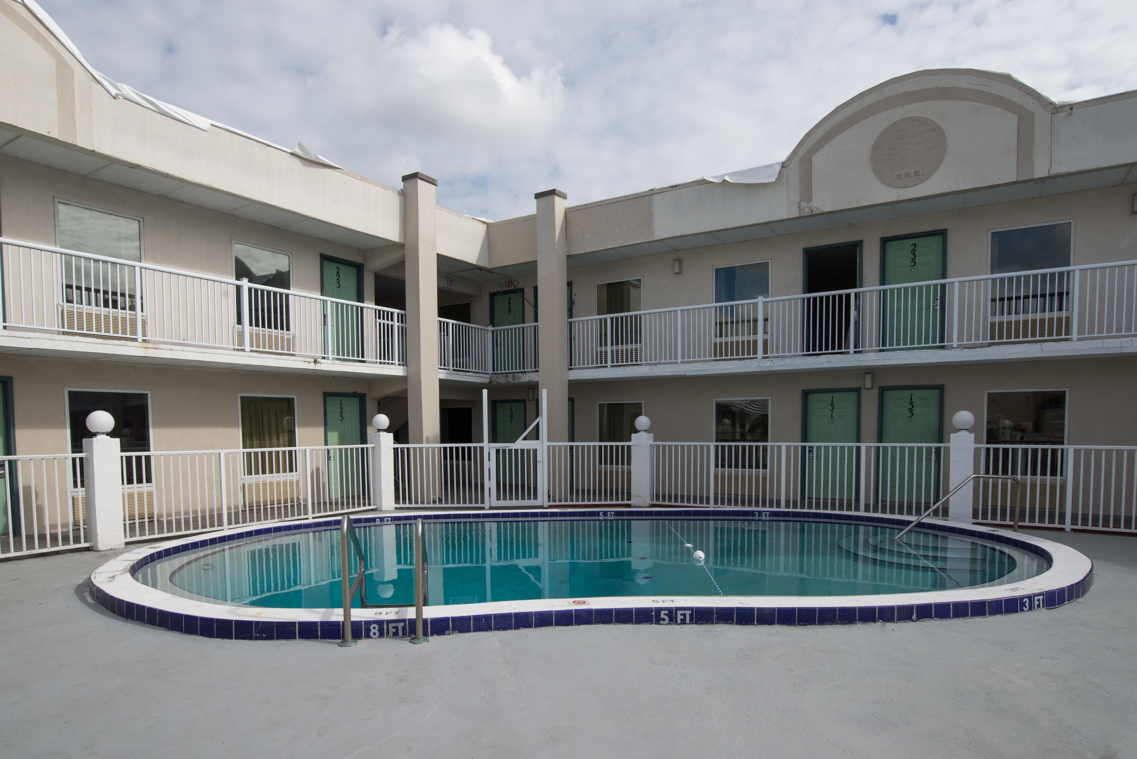 A multi-story hotel with a central swimming pool, balconies, and a uniform exterior design.
