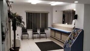 A reception area with a counter, chairs, a potted plant, and a bulletin board.