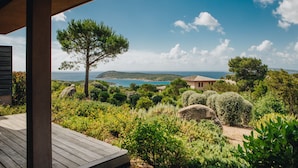 Una terraza de madera con vistas a un paisaje costero, con mar y colinas.