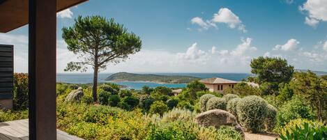 A wooden deck overlooking a coastal landscape with a view of the sea and hills.