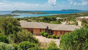 Un resort costero con varias edificaciones, vista despejada al mar y exuberante vegetación.