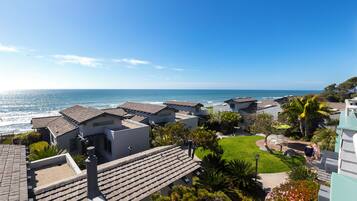 A coastal residential area with houses, a lawn, and a view of the ocean.