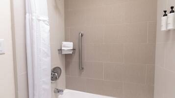 A modern bathroom with a bathtub, a shower with a grab bar, and a towel rack.