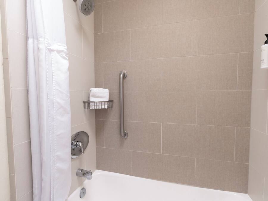 A modern bathroom with a bathtub, a shower with a grab bar, and a towel rack.