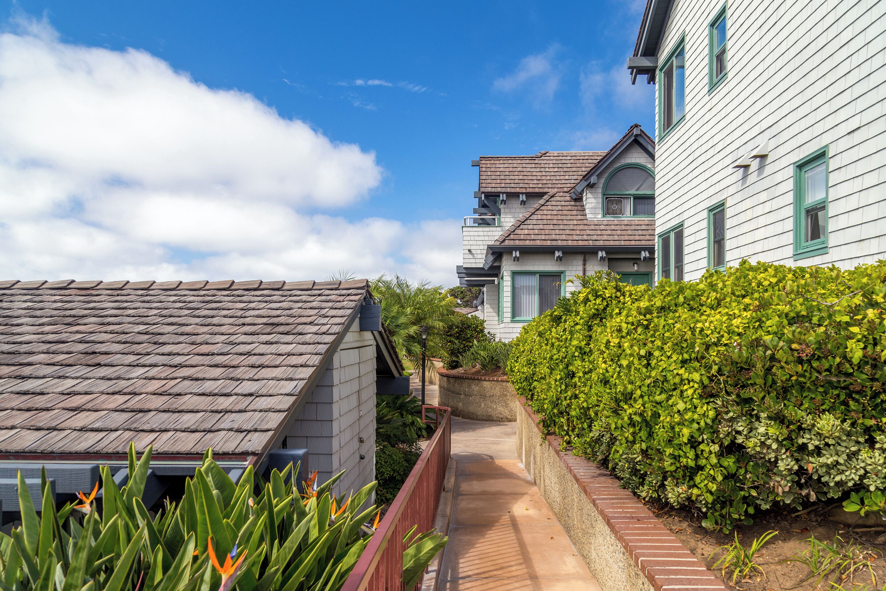 A narrow pathway between two houses with a clear sky above.