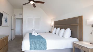 Ein Hotelzimmer mit einem großen Bett, einem Deckenventilator, einem Nachttisch und einem Schreibtisch.