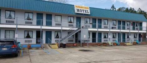 Un motel con techo azul, varios balcones y un estacionamiento.