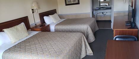 Habitación de hotel con dos camas, un escritorio, una silla, un espejo y un televisor.