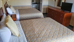 A hotel room with two beds, a dresser, a television, and a mirror. - Traveler's Choice Motel (Bay St Louis)