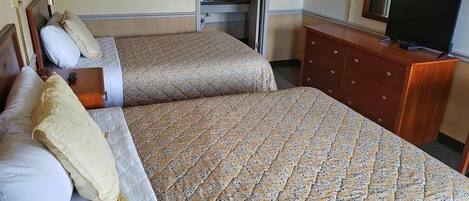 A hotel room with two beds, a dresser, a television, and a mirror.