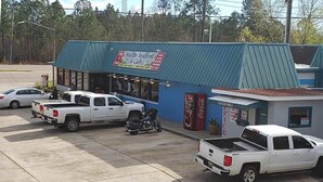 A MacBe Seafood & Cafe with a blue exterior, a Coca-Cola refrigerator, and a small adjacent building labeled 'FEICE'. - Traveler's Choice Motel (Bay St Louis)