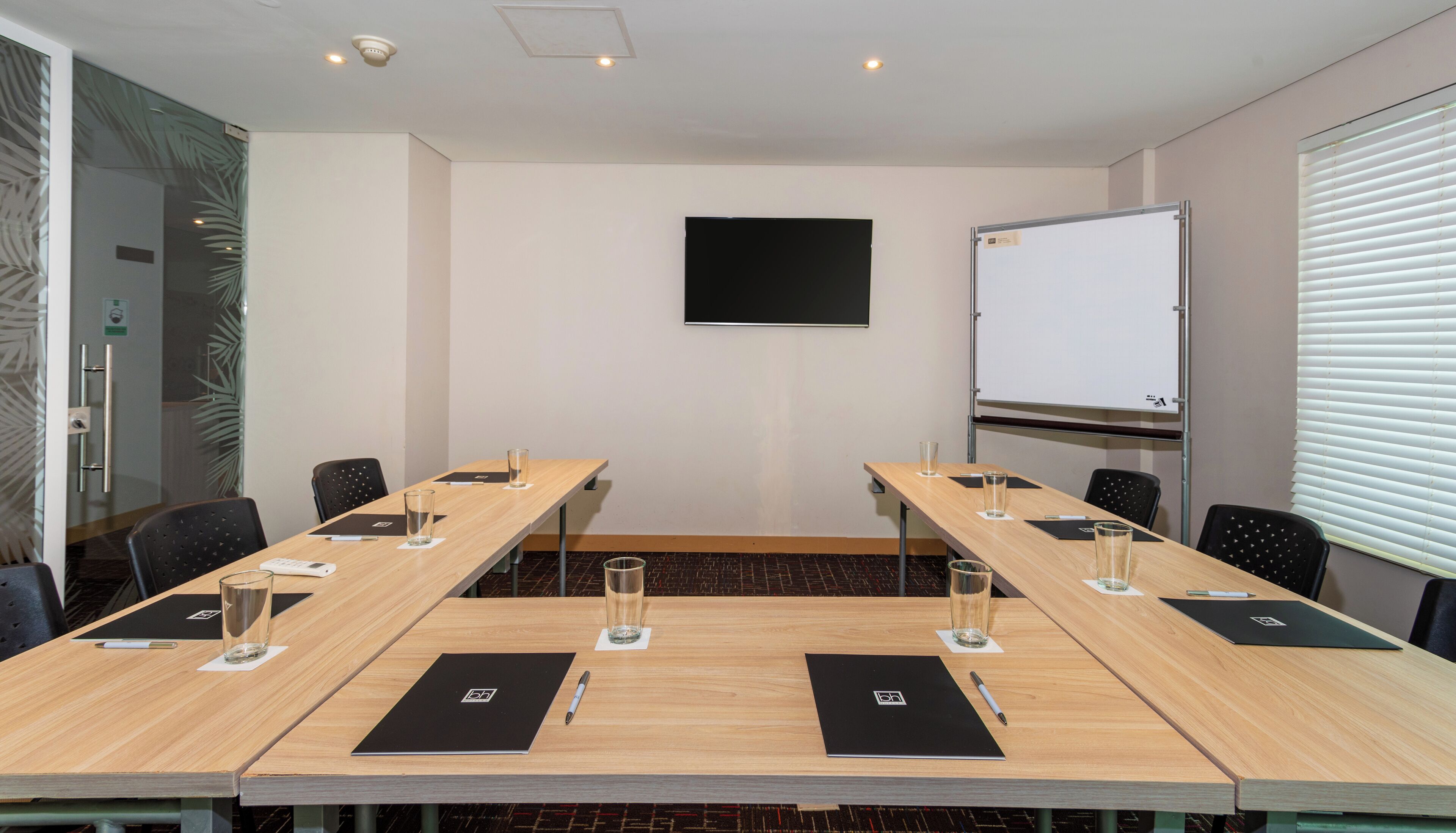 A conference room with a long table, chairs, a whiteboard, and a projector screen.