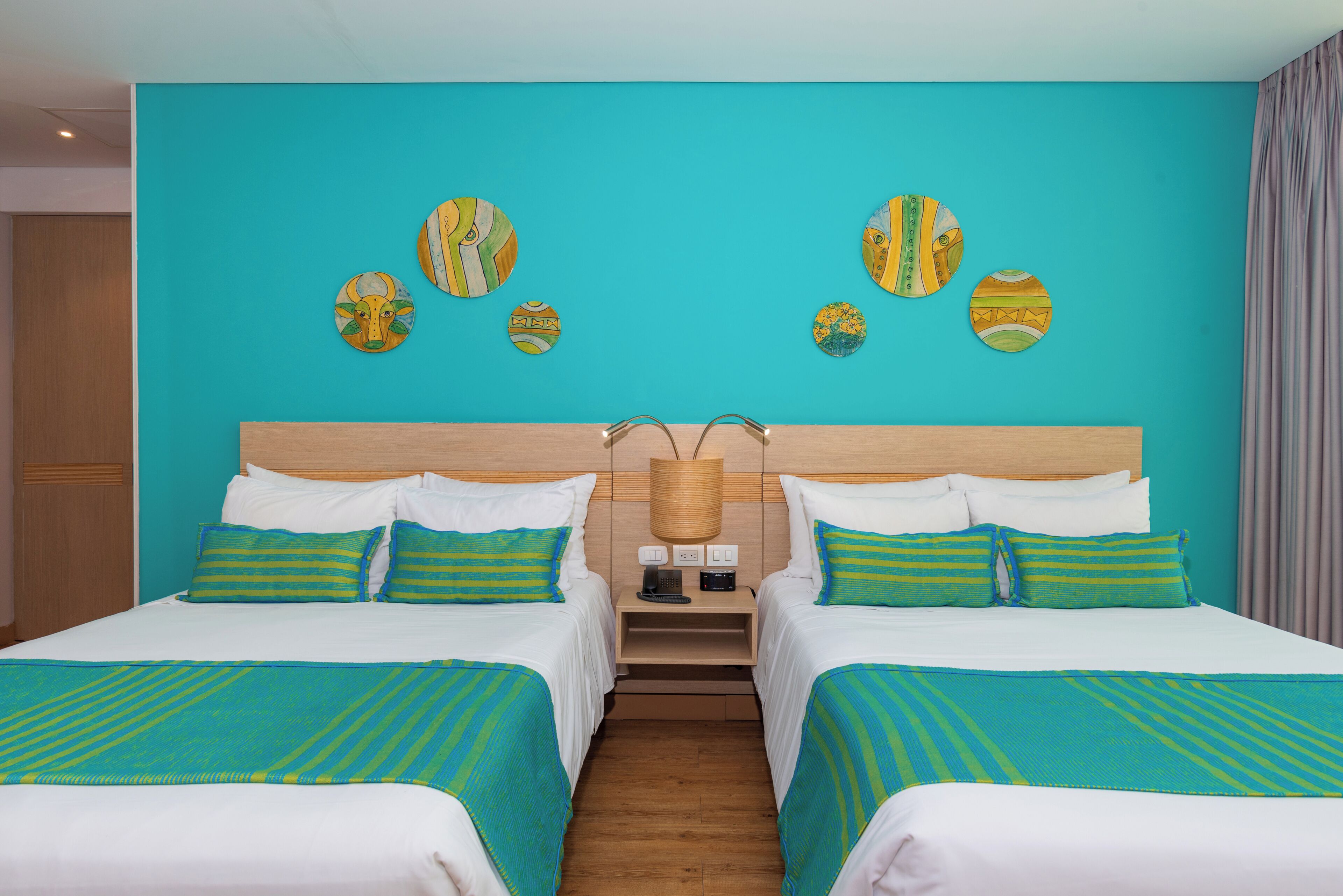 Ein Hotelzimmer mit zwei Betten, einem hölzernen Kopfteil und einer Wand mit dekorativen Tellern.