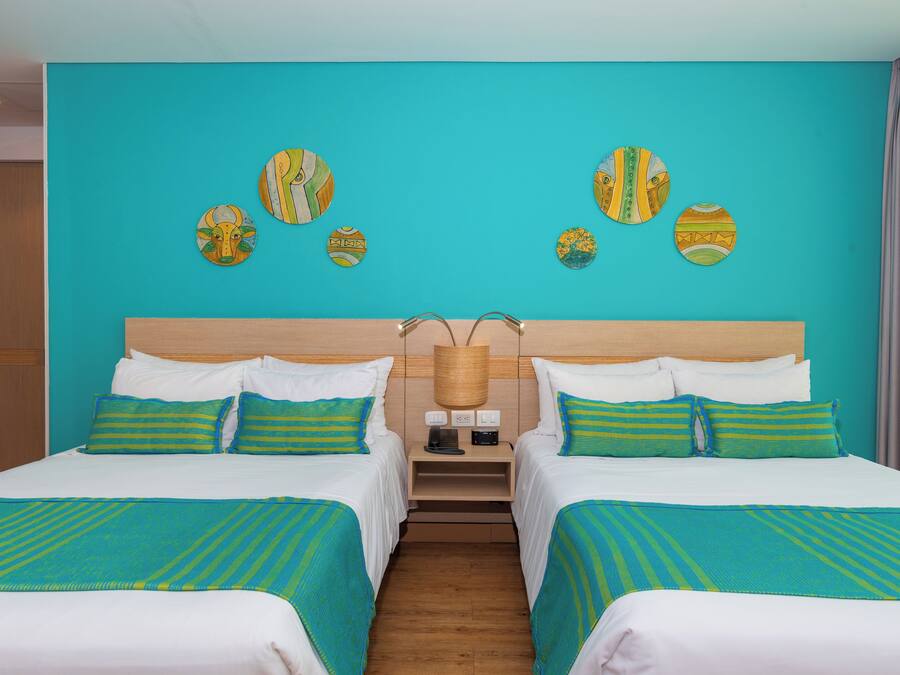 Habitación de hotel con dos camas, un cabecero de madera y una pared decorada con platos.