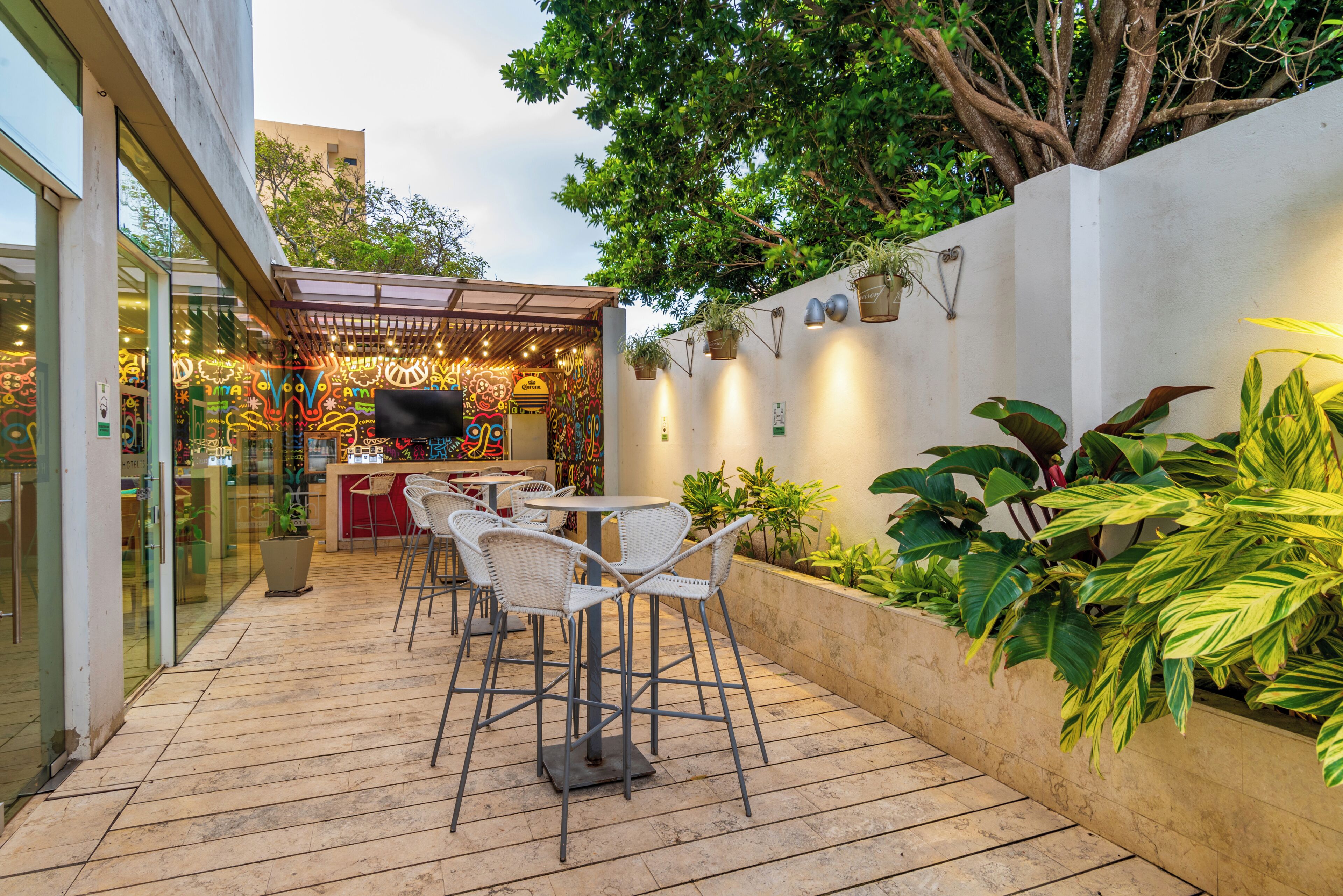 An outdoor patio with a seating area, a bar, and a wall adorned with plants and wall-mounted lights.