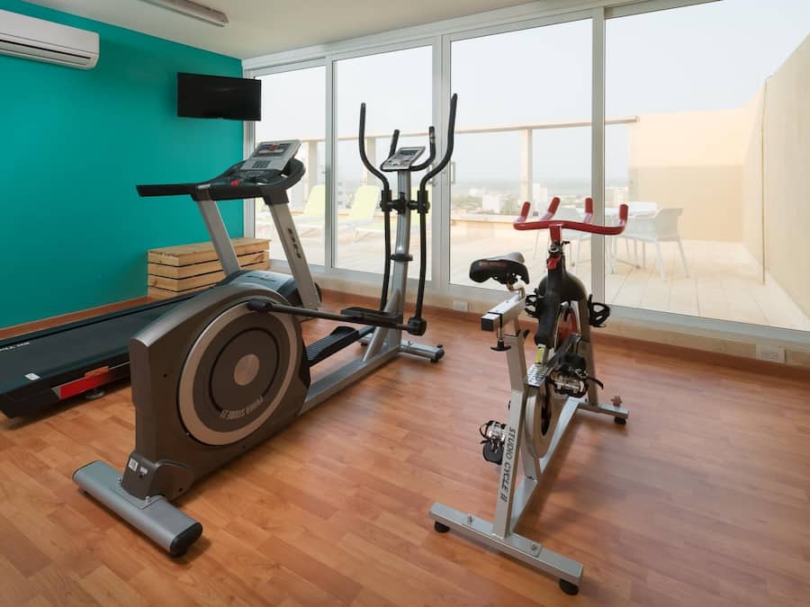 Un gimnasio con máquinas de cardio, una cinta de correr y una bicicleta estática.