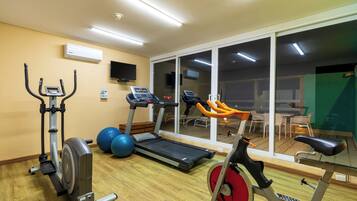 Un gimnasio con equipo de ejercicio, una cinta de correr y un ventanal grande.